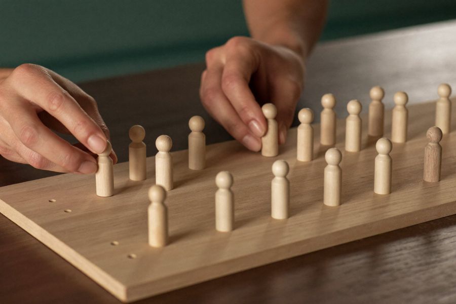 Hände platzieren Holzfiguren auf einem Systembrett