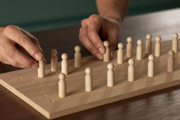 Hände platzieren Holzfiguren auf einem Systembrett
