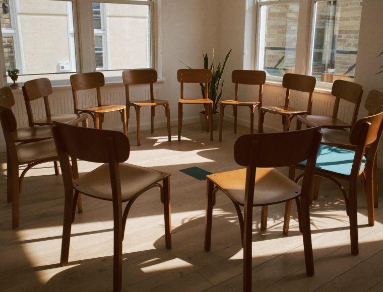 Leerer Stuhlkreis im Morgenlicht als Sinnbild für den geschützten Rahmen einer Familienaufstellung