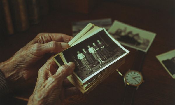 Alte Hände halten Schwarz-Weiß-Familienfotos