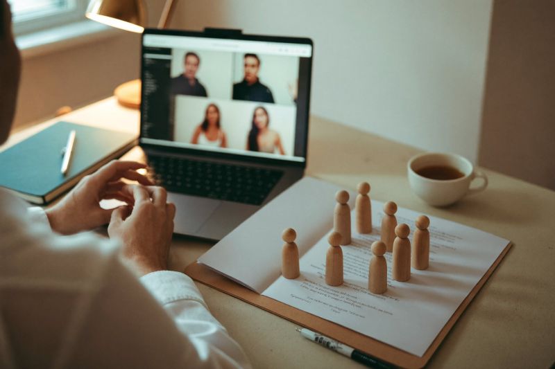 Online-Beratung am Laptop mit Holzfiguren auf dem Schreibtisch