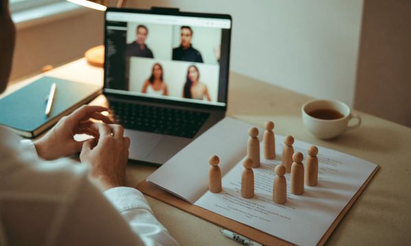 Laptop-Videokonferenz mit Figuren auf dem Schreibtisch