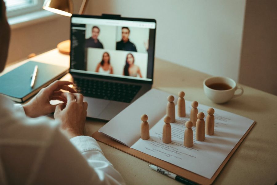 Laptop-Videokonferenz mit Aufstellungsfiguren auf dem Schreibtisch