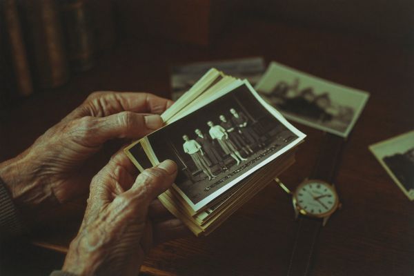 Alte Hände halten schwarz-weiße Familienfotos